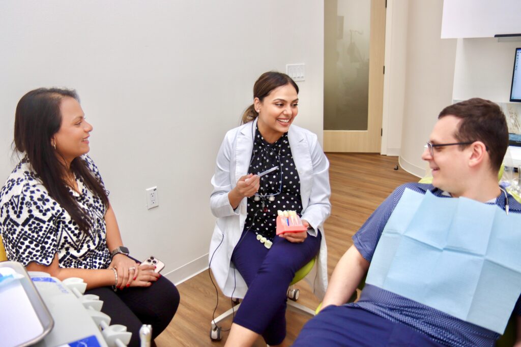 A dentist smiling with two paitent in the dental - Evergreen dental TX
